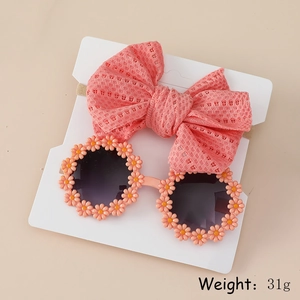 Baby fashion set with hollow bow headband and daisy sunglasses on beige background