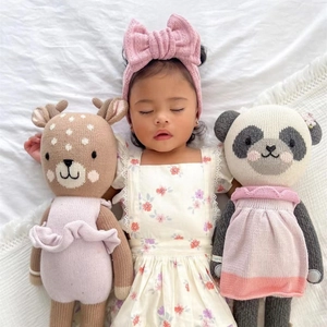 Detail view of pink knit baby headband with oversized bow and soft animal plush toys