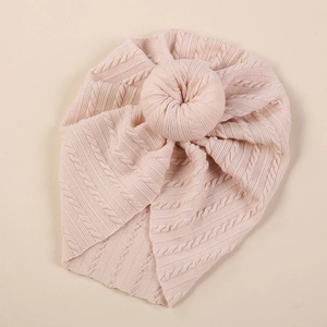 Detail of baby donut turban hat featuring light pink cable knit texture and soft knot