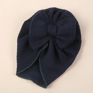Detail view of navy blue baby turban hat with oversized bow and green stitching