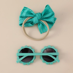 Baby turquoise lace bow headband and sunflower sunglasses set on a beige background