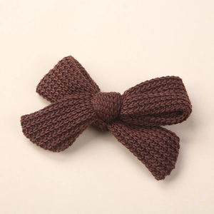 Close-up of a dark coffee knitted bow hair clip featuring soft woolen texture and weave