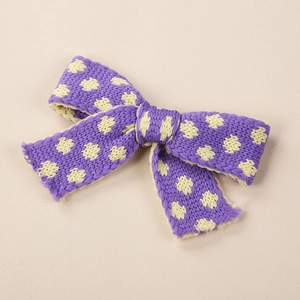 Dettaglio ravvicinato di un fiocco per capelli in maglia viola con pois gialli