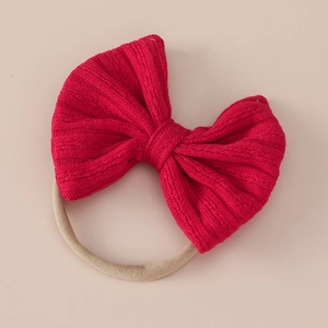 Detailed view of red jacquard knitted bow headband with soft nude nylon hair band