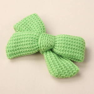 Detail view of light green knitted bow hair clip featuring intricate woven texture