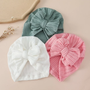 Three rib-knit baby turbans with large bows in white, pink, and bean green colors
