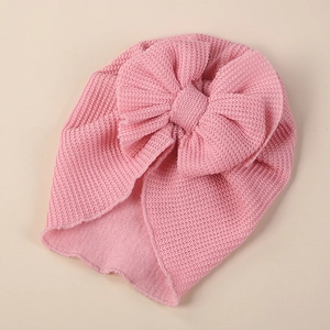 Detailed close-up of pink knit baby turban hat with a large bow and warm fleece lining