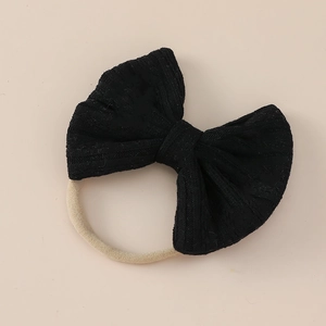 Detailed close-up of a black jacquard bow on a soft nylon headband for babies