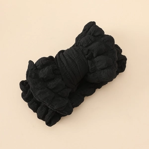 Détail de la texture du bandeau bébé noir avec grand nœud en tissu gaufré élastique