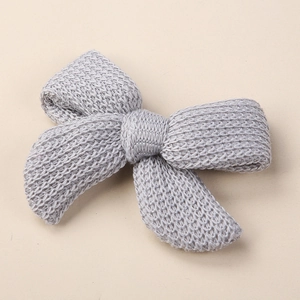 Detailed view of handmade light grey knitted bow hair clip with soft woolen texture