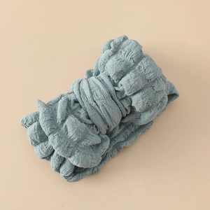Détail montrant la texture plissée du bandeau pour bébé en tissu bleu doux de près