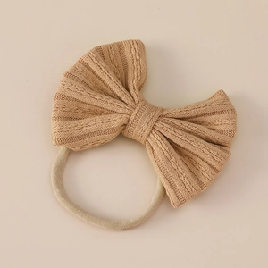 Detailed close-up of light khaki jacquard knit bow with soft nylon baby headband texture