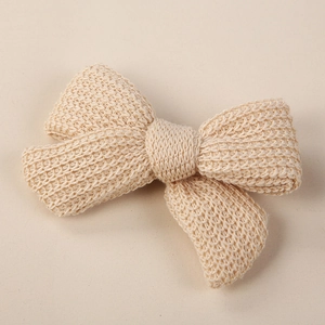 Macro shot of knitted off-white bow hair clip showing dense texture and soft craft details