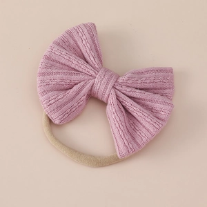 Detail of pink cable knit baby headband with soft texture and seamless nylon elastic band