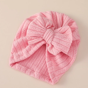 Close-up of the knitted texture and oversized bow on this pink baby turban hat