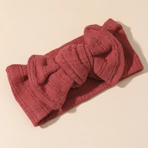 Dettaglio della fascia per neonata in maglia con grande fiocco color rosso scuro