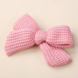 Close-up of pink knitted bow hair clip featuring fine needlework and soft texture