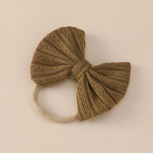 Detailed close-up of a caramel jacquard bow headband with soft nylon elastic texture