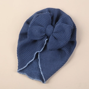 Detail of baby turban hat showing deep blue waffle knit fabric and large decorative bow