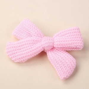 Detail of pink knitted bow hair clip showing soft yarn texture and crochet pattern