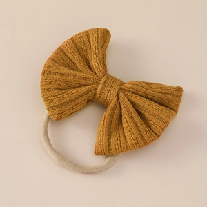 Detail of soft jacquard knit bow headband in ginger yellow for babies with elastic nylon band
