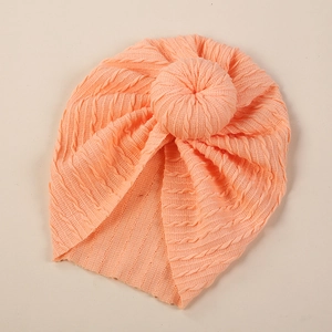 Detail of baby donut turban hat featuring coral knitted texture and decorative twist knot