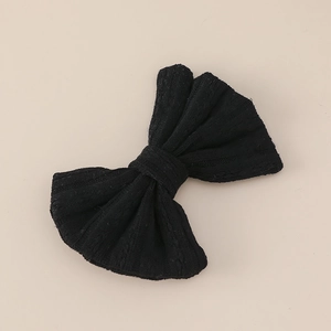 Detail of black knitted bow hair clip with fine vertical striped texture for girls