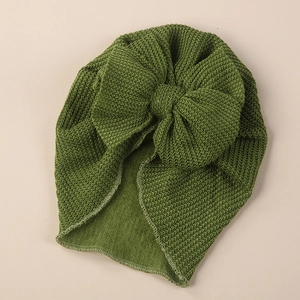 Close-up detail of grass green knit baby turban hat with a large decorative bow