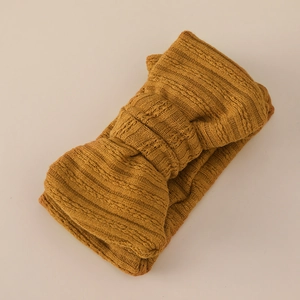 Detailed view of ginger yellow jacquard knit baby headband with double-layered bow