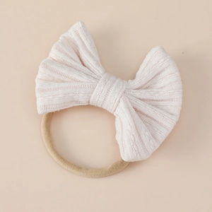Detail of soft ribbed knit baby headband with oversized bow and elastic nylon band
