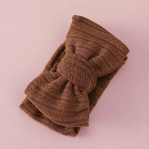 Detail view of dark brown knitted baby headband with a large textured double bow