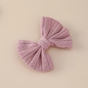 Detailed close-up of light pink knitted bow hair clip with jacquard knit texture