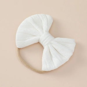 Detailed macro view of white textured knit bow baby headband with elastic nylon band