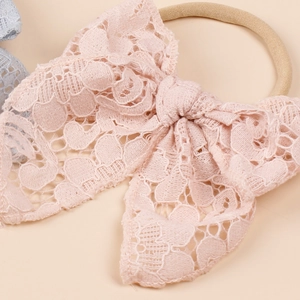 Pale pink baby headband with a hollow lace bow and elastic nylon band for girls