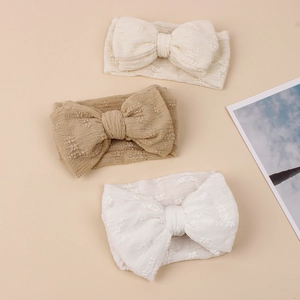 Détails de trois bandeaux tricotés pour bébé avec nœuds en couleurs crème, avoine et blanc