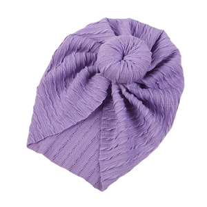 Purple cable knit baby turban hat with a large donut knot on a plain white background