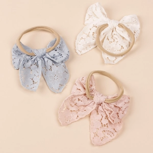 Detailed close-up of lace bow baby headbands in blue, white, and pink nylon