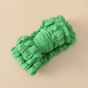 Gros plan détaillé du bandeau bébé vert en tissu gaufré élastique sur fond uni