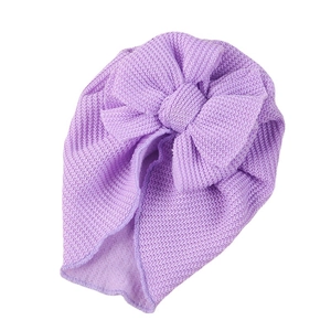 Purple waffle knit baby turban hat with a large double bow decoration on white background