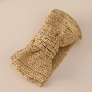 Detailed close-up of beige knitted baby headband with a double-layered jacquard bow