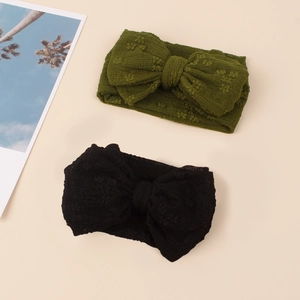 Détail de bandeaux pour bébé avec nœuds en tricot jacquard en vert armée et noir sur beige