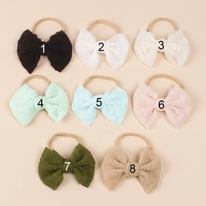 Detailed flat lay of eight soft nylon baby headbands with textured lace bows in various colors