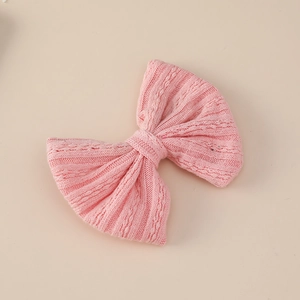 Detail showing the pink knitted texture and jacquard weave pattern of the bow hair clip
