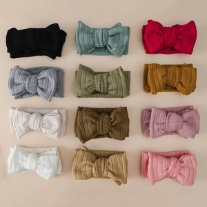 Set of 12 ribbed baby headbands with large bows in various colors laid in grid