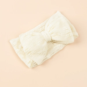 Détail d'un bandeau pour bébé avec nœud en tricot texturé de couleur ivoire et élastique