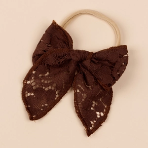 Detailed close-up of dark brown hollow lace bow headband with vintage nylon texture