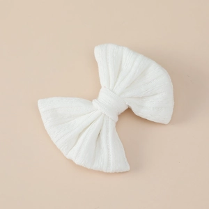 Close-up of white knitted bow hair clip featuring soft ribbed texture for baby girls