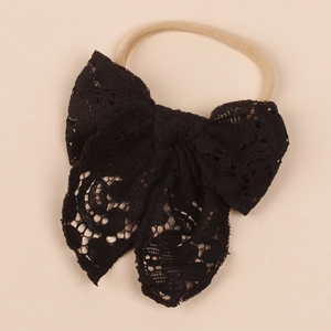 Detail of baby lace bow headband featuring hollow-out embroidery and soft nylon strap