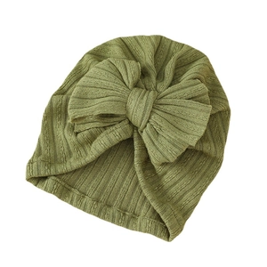 Green striped knit baby turban hat with a large decorative bow on a white background