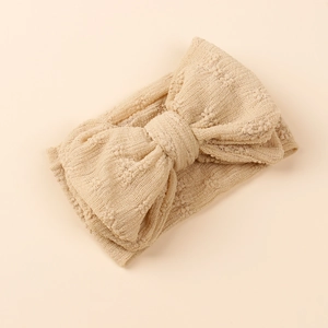 Vue détaillée d'un bandeau en maille crochetée abricot avec un nœud doux texturé